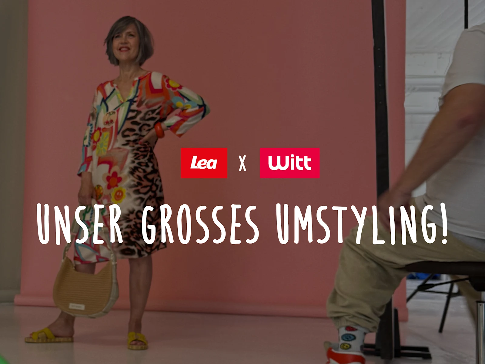 Ein Bild mit dem Text 'Unser großes Umstyling!'. Der Hintergrund zeigt ein Fotoshooting-Set mit rosa Hintergrund. Links steht eine Frau in einem farbenfrohen Kleid und gelben Schuhen, sie hält eine Tasche in der Hand. Rechts im Vordergrund sitzt eine Person auf einem Hocker. In der Mitte sind die Logos von Lea und Witt zu sehen.