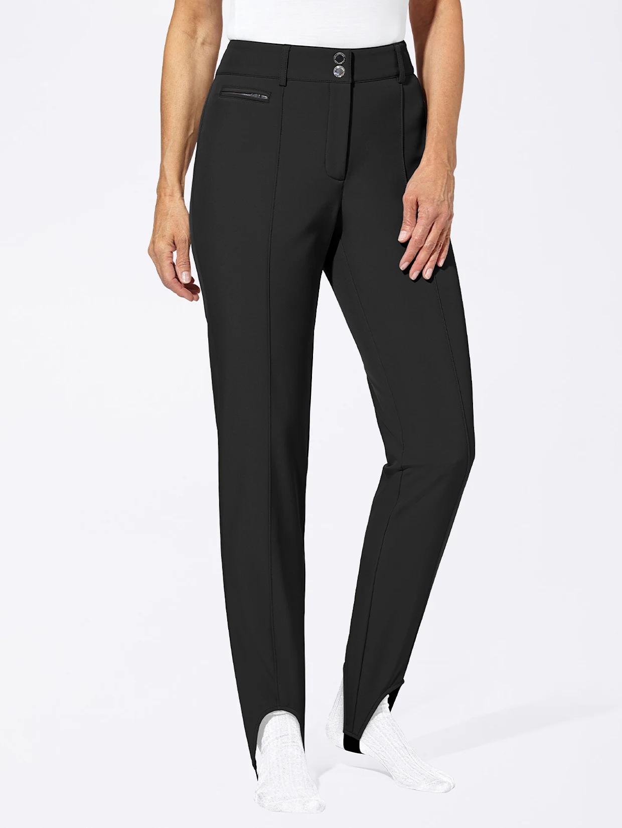 Schwarze Damenhose mit geradem Schnitt, seitlichen Reißverschlusstaschen und elastischen Fußschlaufen, getragen mit weißen Socken. Schwarze Damenhose mit geradem Schnitt, seitlichen Reißverschlusstaschen und elastischen Fußschlaufen, getragen mit weißen Socken.