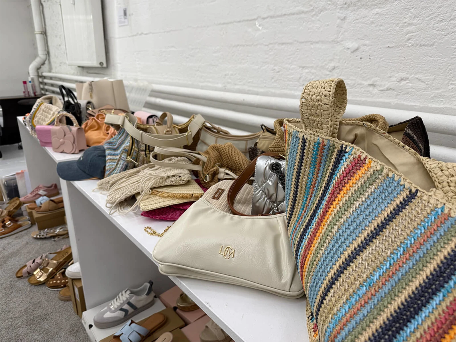 Handtaschen, Sandalen und Sneaker stehen dicht gedrängt auf einem weißen Regal. Handtaschen, Sandalen und Sneaker stehen dicht gedrängt auf einem weißen Regal.