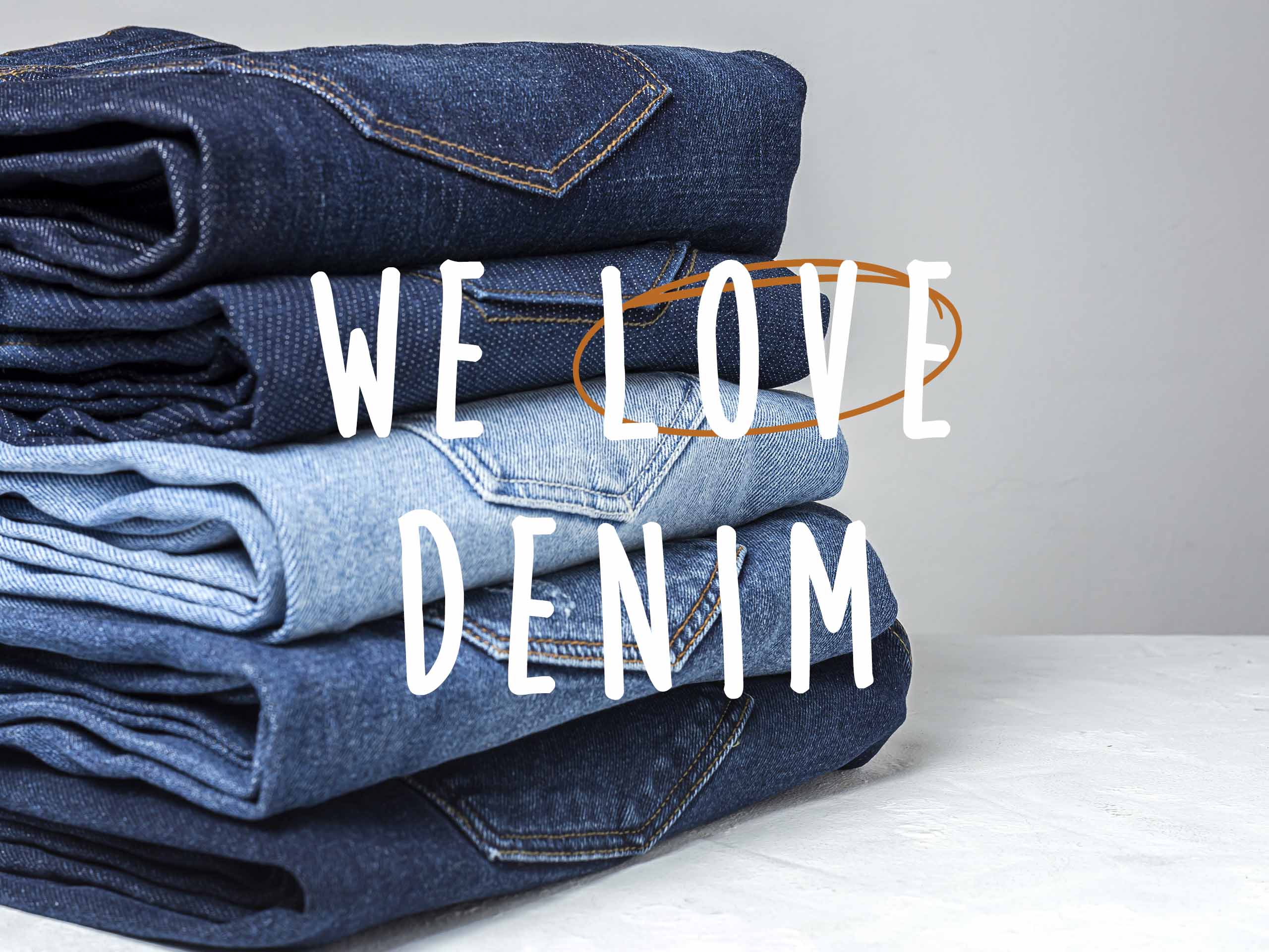 Ein Stapel gefalteter Jeans in verschiedenen Blautönen mit dem Text "WE LOVE DENIM".