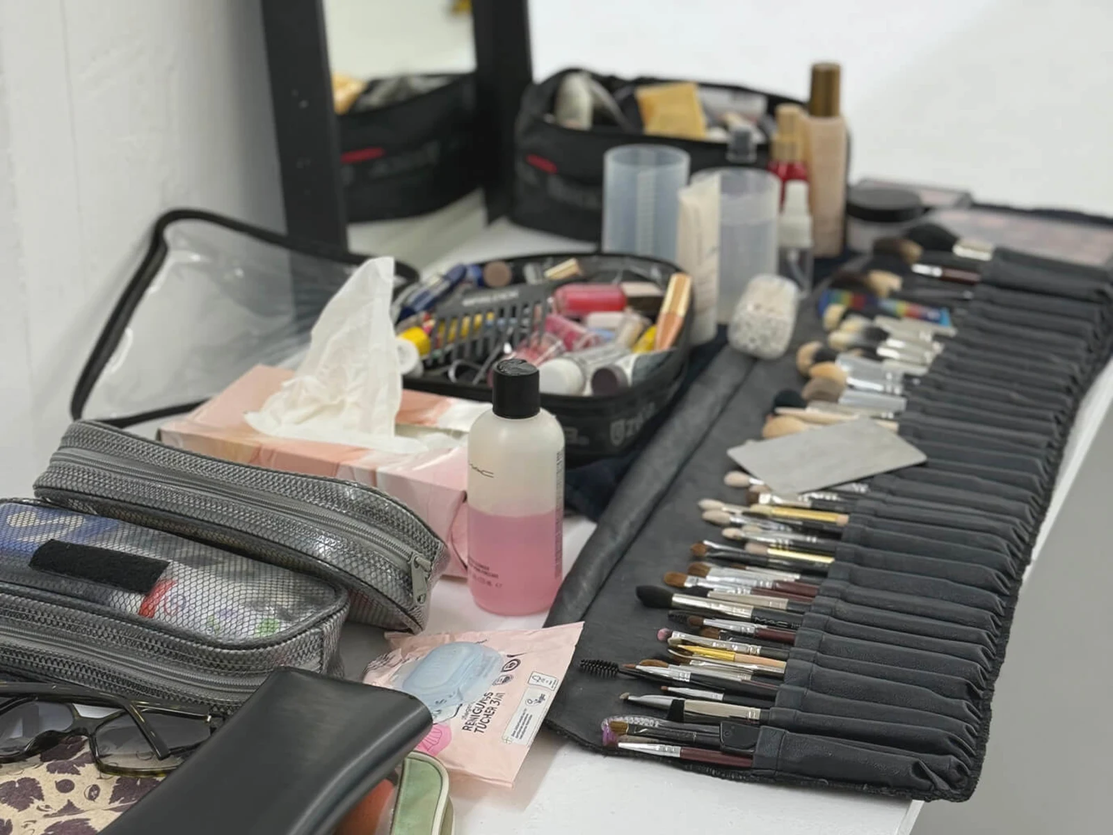 Ein Tisch mit verschiedenen Make Up Produkten, Pinseln und Kosmetiktaschen. Ein Tisch mit verschiedenen Make Up Produkten, Pinseln und Kosmetiktaschen.