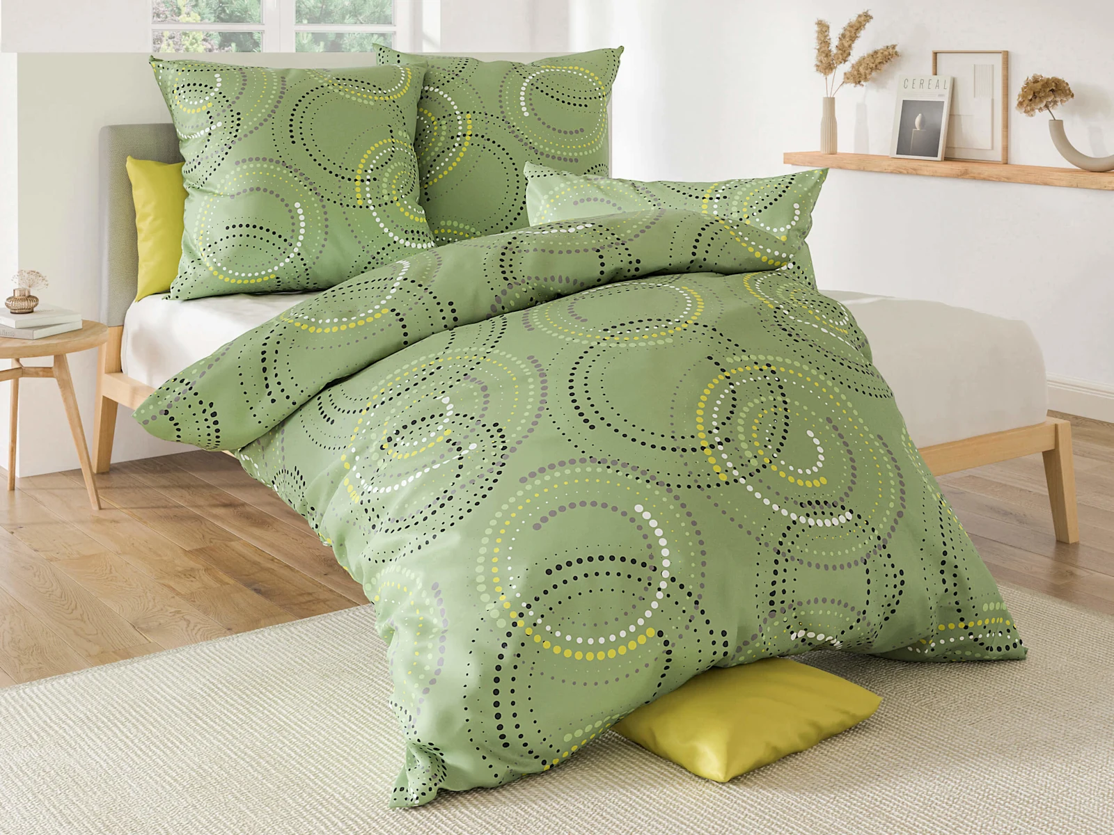 Ein Bett mit grün gemusterter Bettwäsche, bestehend aus Kissenbezügen und Decke, in einem hellen, modernen Schlafzimmer.