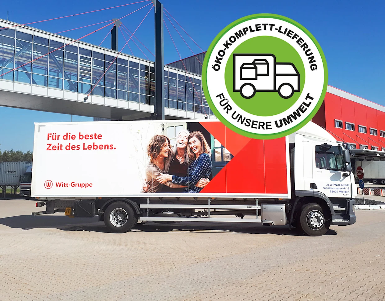 LKW der Witt-Gruppe mit Werbebotschaft "Für die beste Zeit des Lebens" und Öko-Komplett-Lieferung-Logo, im Hintergrund moderne Gebäude und blauer Himmel. LKW der Witt-Gruppe mit Werbebotschaft "Für die beste Zeit des Lebens" und Öko-Komplett-Lieferung-Logo, im Hintergrund moderne Gebäude und blauer Himmel.