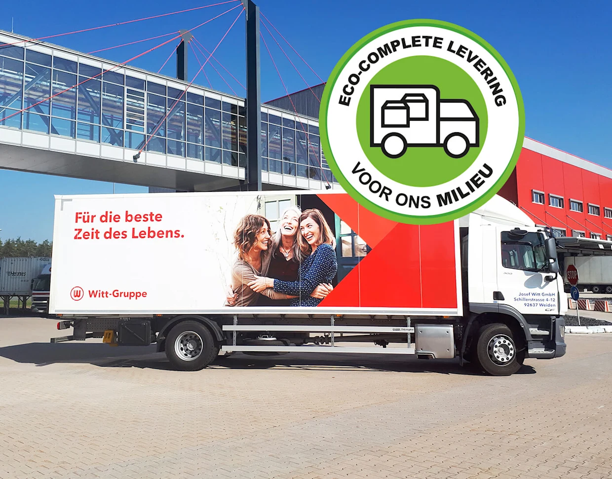 Vrachtwagen van de Witt-Groep met rode en witte reclameopdruk, geparkeerd voor een modern gebouw en een loopbrug, met een groene badge die milieuvriendelijke levering benadrukt. Vrachtwagen van de Witt-Groep met rode en witte reclameopdruk, geparkeerd voor een modern gebouw en een loopbrug, met een groene badge die milieuvriendelijke levering benadrukt.