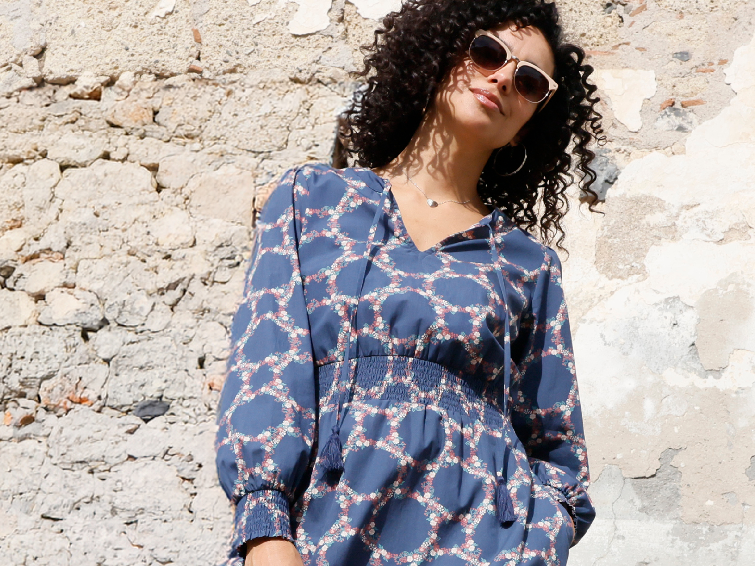 Model in rauchblau bedrucktem Kleid mit Smokbund in der Taille