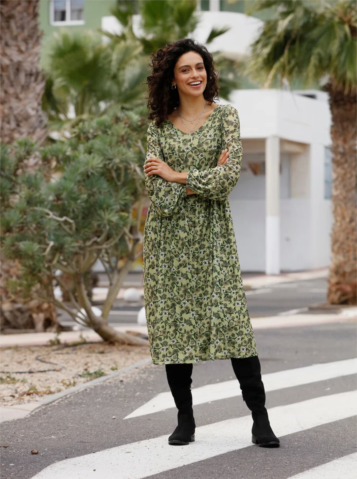 Frau trägt ein grünes Blumenkleid in floral bedruckter Mesh-Qualität. Im Hintergrund sind Palmen und ein Gebäude zu sehen.
Frau trägt ein grünes Blumenkleid in floral bedruckter Mesh-Qualität. Im Hintergrund sind Palmen und ein Gebäude zu sehen.
