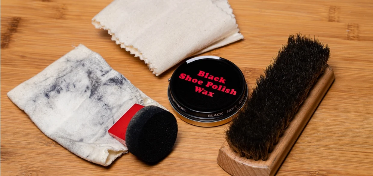 Schuhputz-Set mit schwarzer Schuhcreme, Bürste, Schwamm und Tuch auf Holztisch. Schuhputz-Set mit schwarzer Schuhcreme, Bürste, Schwamm und Tuch auf Holztisch.