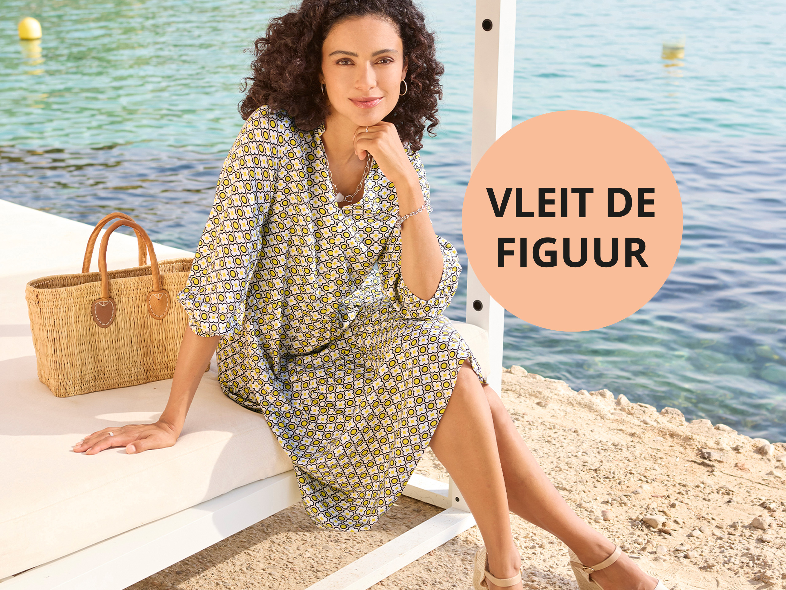 Vrouw in zomerjurk met print bij de zee. Tekst in cirkel: „VLEIT DE FIGUUR“. Zonnige, zomerse sfeer.