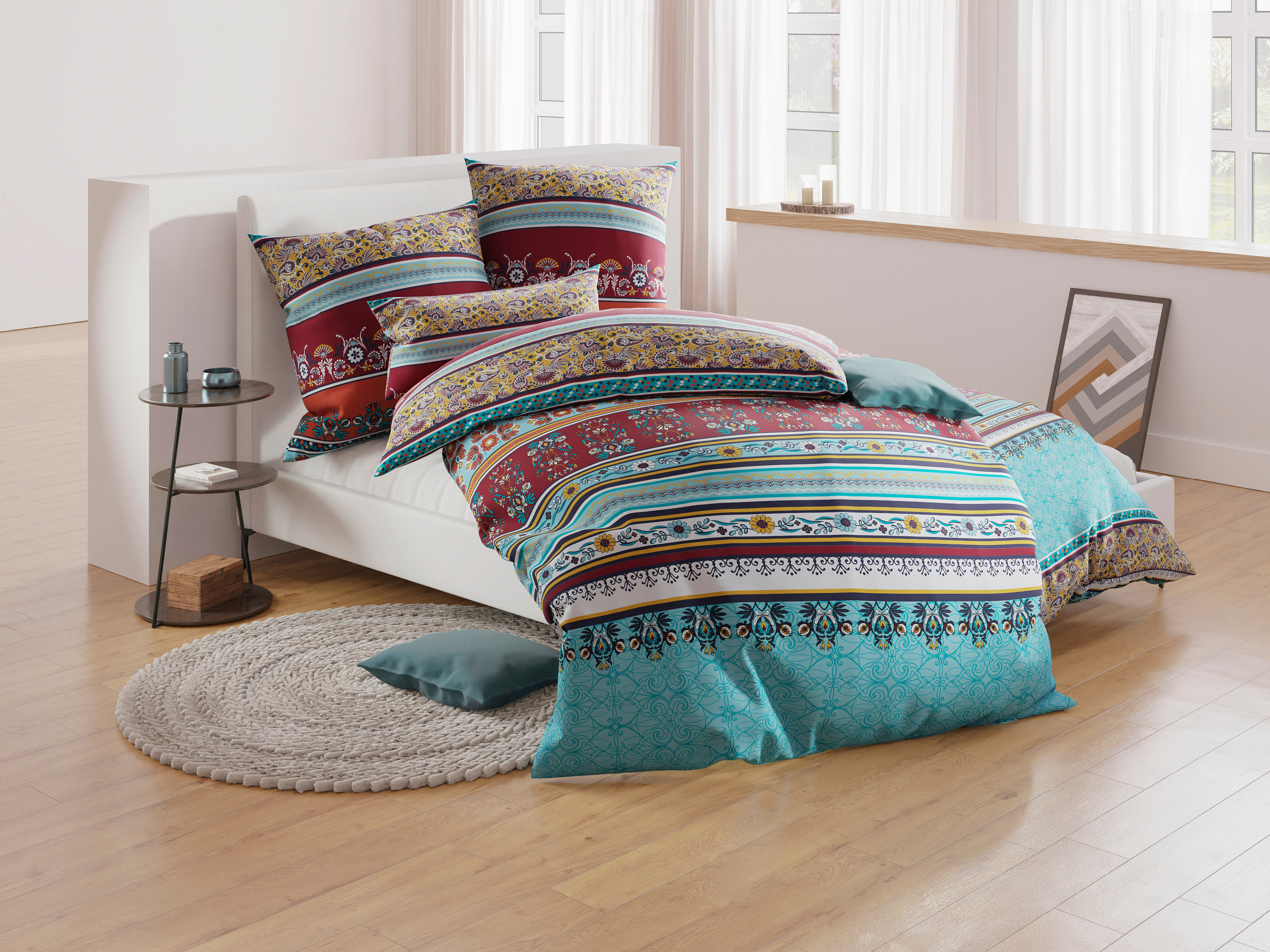 türkis-rot-beige gemusterte Bettwäsche auf einem Bett