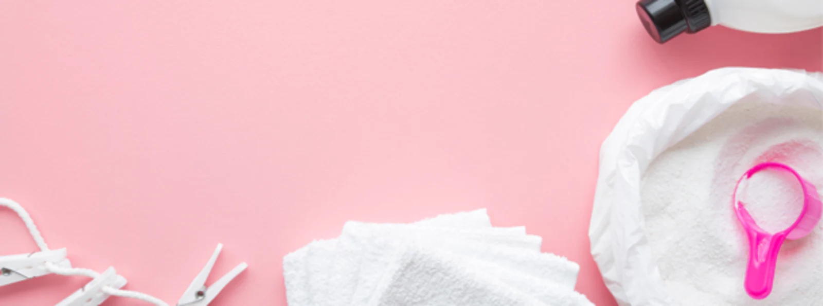 Waschmittel, Messlöffel, weiße Handtücher und Wäscheklammern auf rosa Hintergrund. Waschmittel, Messlöffel, weiße Handtücher und Wäscheklammern auf rosa Hintergrund.