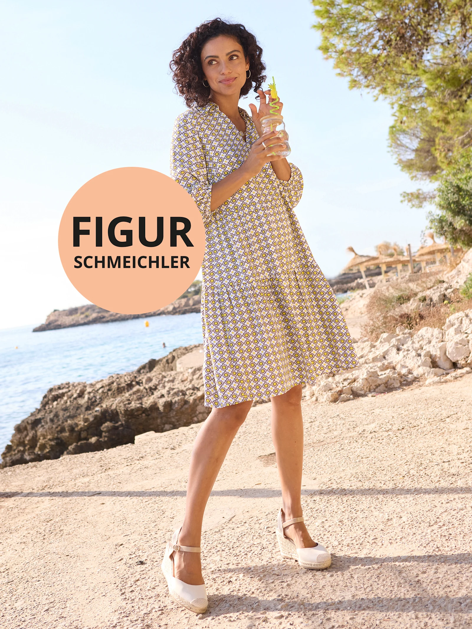 Stehende Frau in gemustertem Kleid am Strand. Text im Kreis: „FIGURSCHMEICHLER“. Sonnig-mediterrane Kulisse.