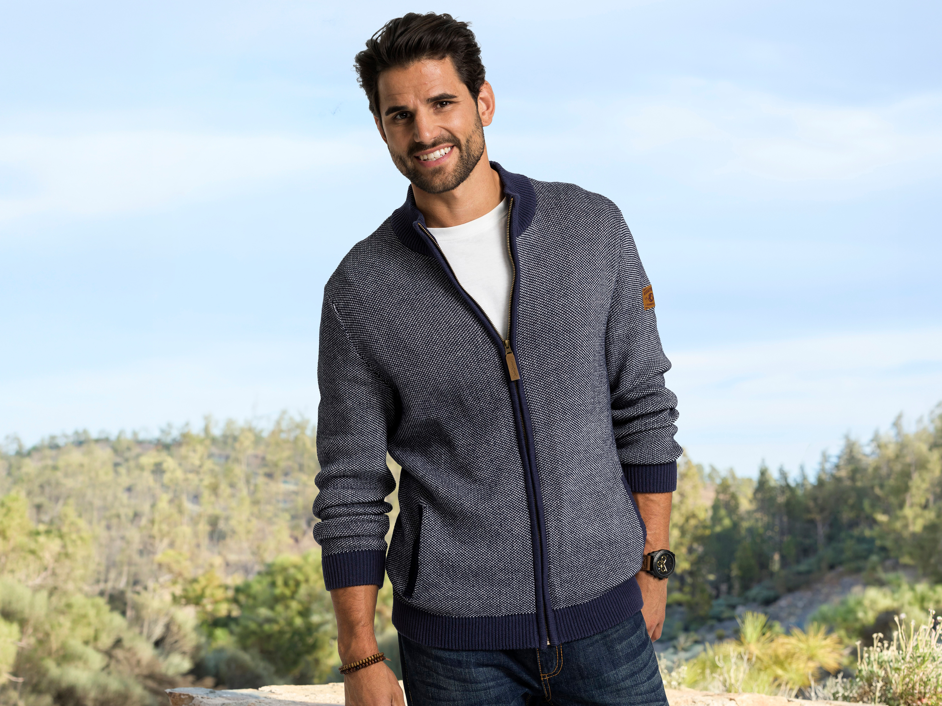Ein männliches Model trägt eine blaue Zipperjacke