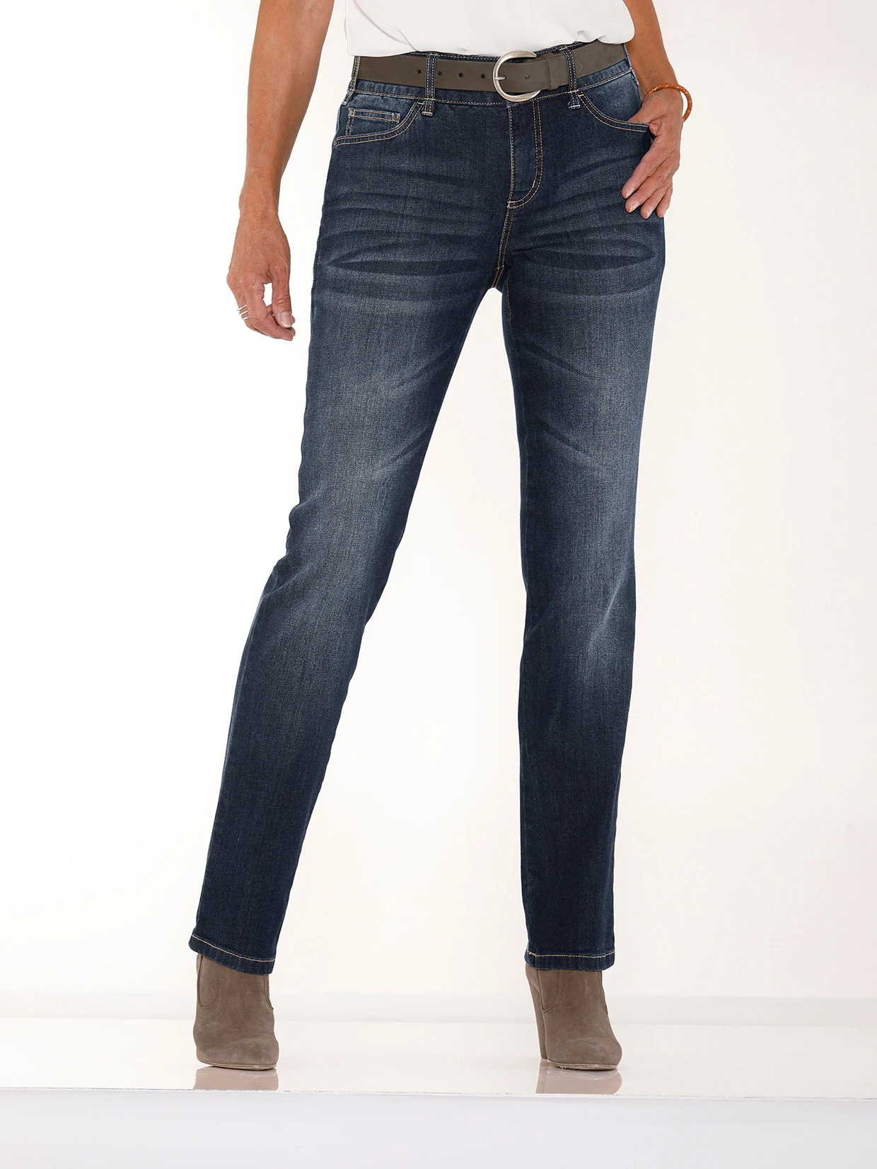 Dunkelblaue Damen-Jeans mit geradem Schnitt, kombiniert mit braunem Gürtel und beigefarbenen Stiefeletten.