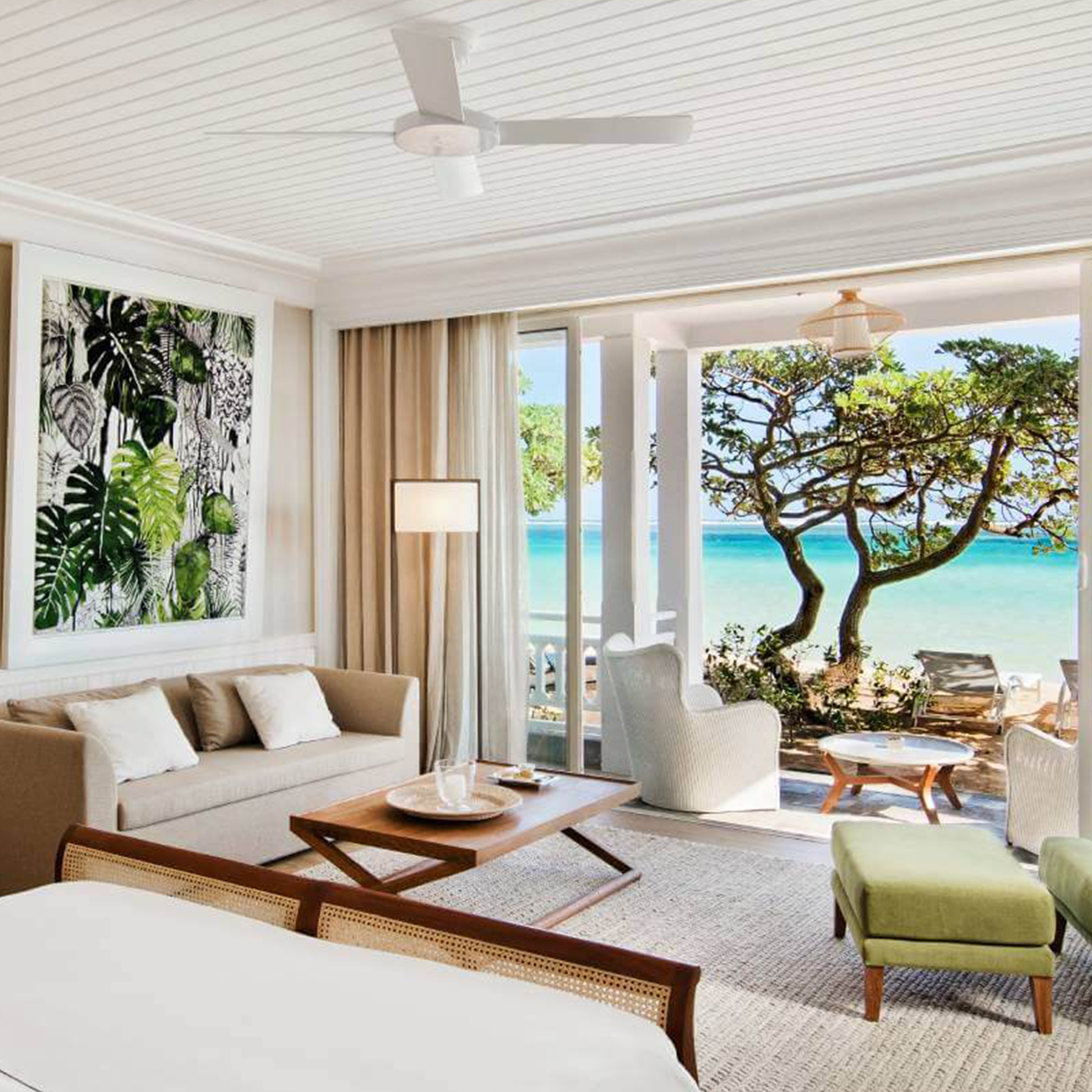 Helles Zimmer mit Sitzecke, großem Fenster und Blick auf das Meer. Moderne Einrichtung, Naturmotive an der Wand.