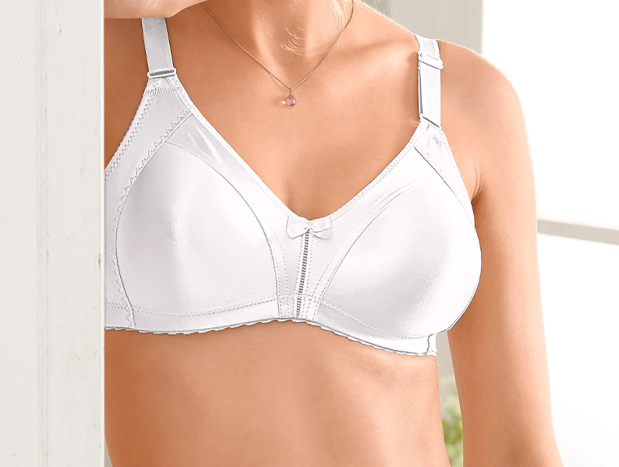 Frau trägt einen weißen, bügellosen BH mit dekorativer Schleife und verstellbaren Trägern.