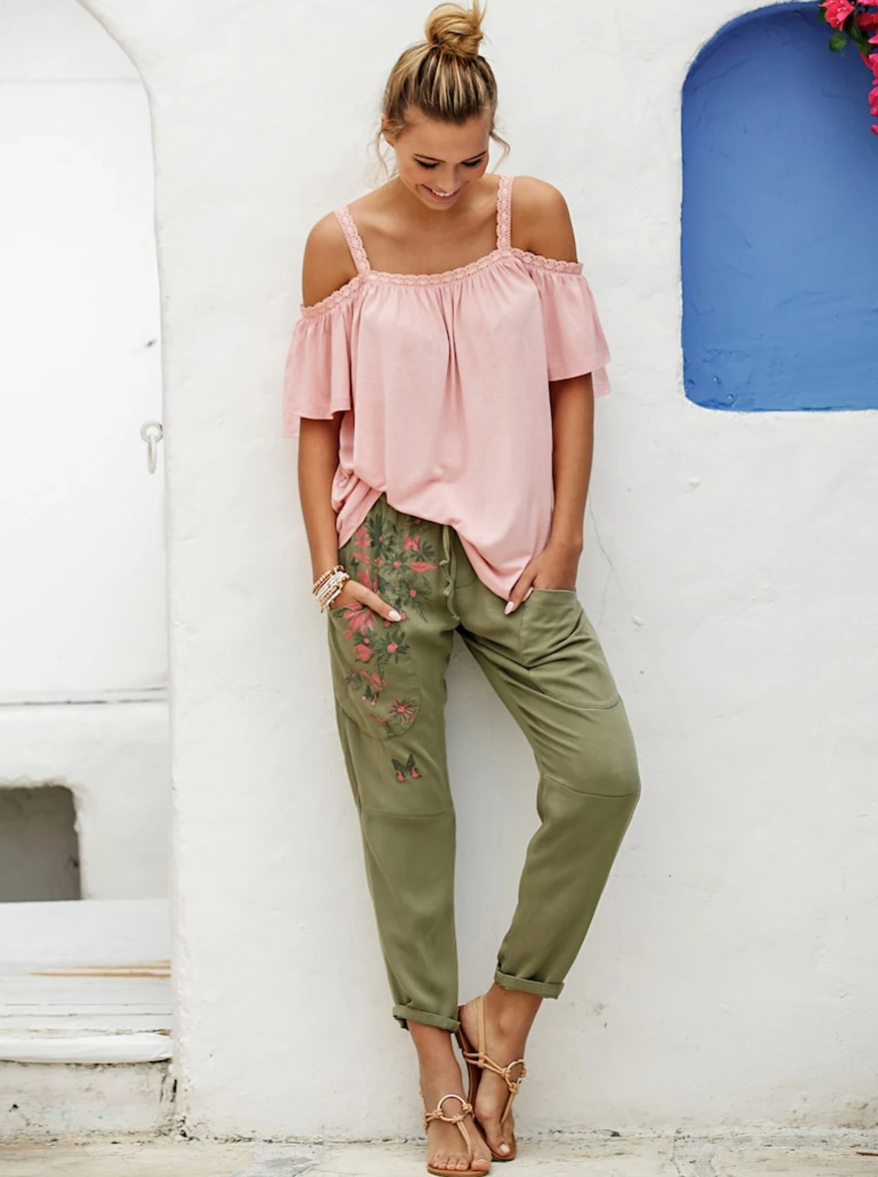Frau mit rosa Carmenbluse und grüner Schlupfhose mit Blumen- und Schmetterlings-Druck vorne. Frau mit rosa Carmenbluse und grüner Schlupfhose mit Blumen- und Schmetterlings-Druck vorne.
