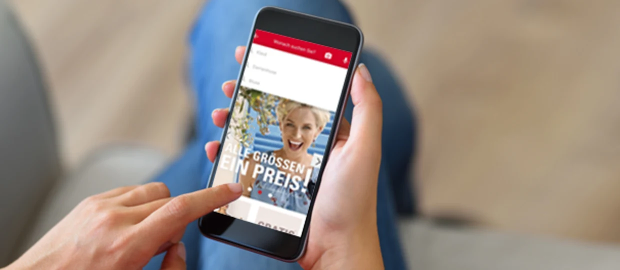 Person hält ein Smartphone, auf dem eine Shopping-App mit der Aufschrift "Alle Größen ein Preis" angezeigt wird. Person hält ein Smartphone, auf dem eine Shopping-App mit der Aufschrift "Alle Größen ein Preis" angezeigt wird.