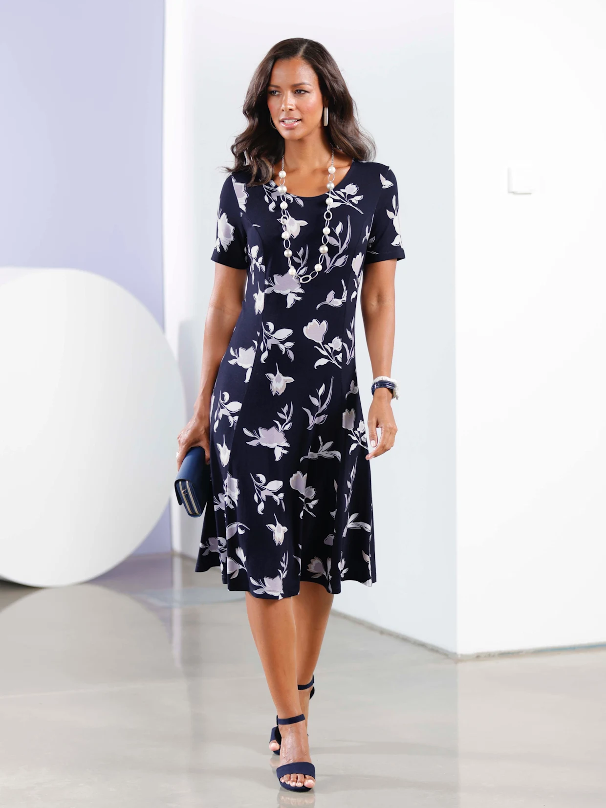 Frau mit knielangem dunkelblauem Kleid mit weißen Blattmuster