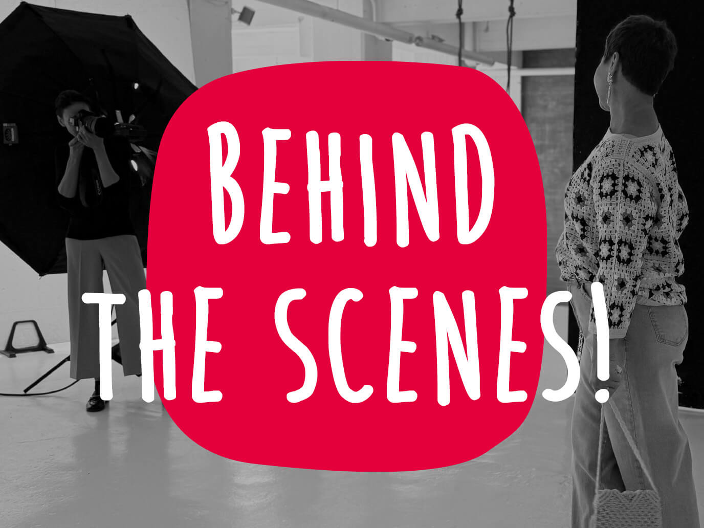 Ein Bild mit schwarz-weißem Hintergrundfoto und rotem Textfeld mit dem Text 'Behind the Scenes!'. Der Hintergrund zeigt eine Szene aus einem Fotoshooting: Links steht eine Fotografin mit Kamera und Studiolicht, rechts eine Frau im gemusterten Pullover und Jeans, das rote Textfeld hebt den Schriftzug hervor.