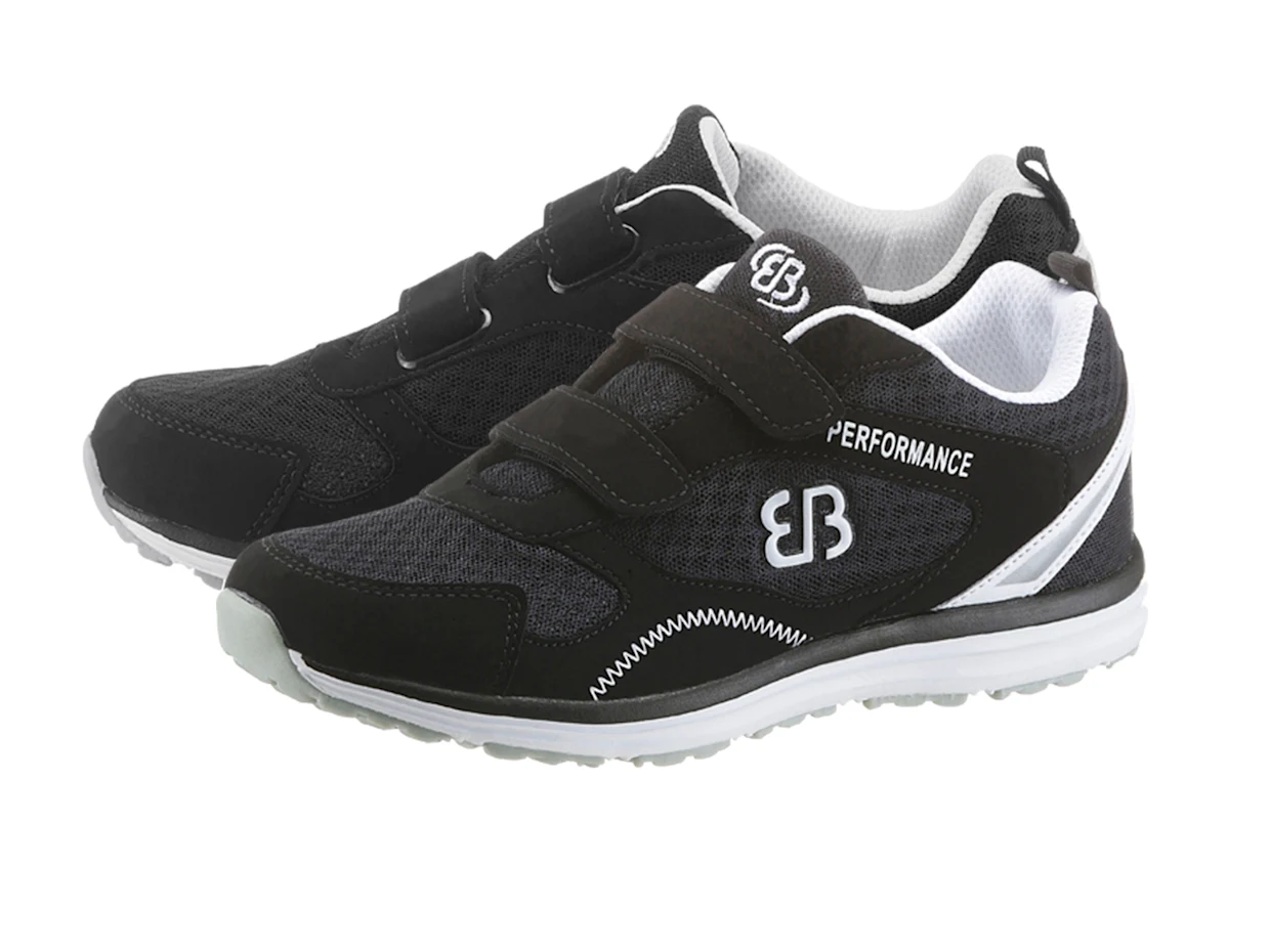 Schwarze Sportschuhe mit Klettverschluss, weißer Sohle und "Performance"-Logo seitlich. Schwarze Sportschuhe mit Klettverschluss, weißer Sohle und "Performance"-Logo seitlich.