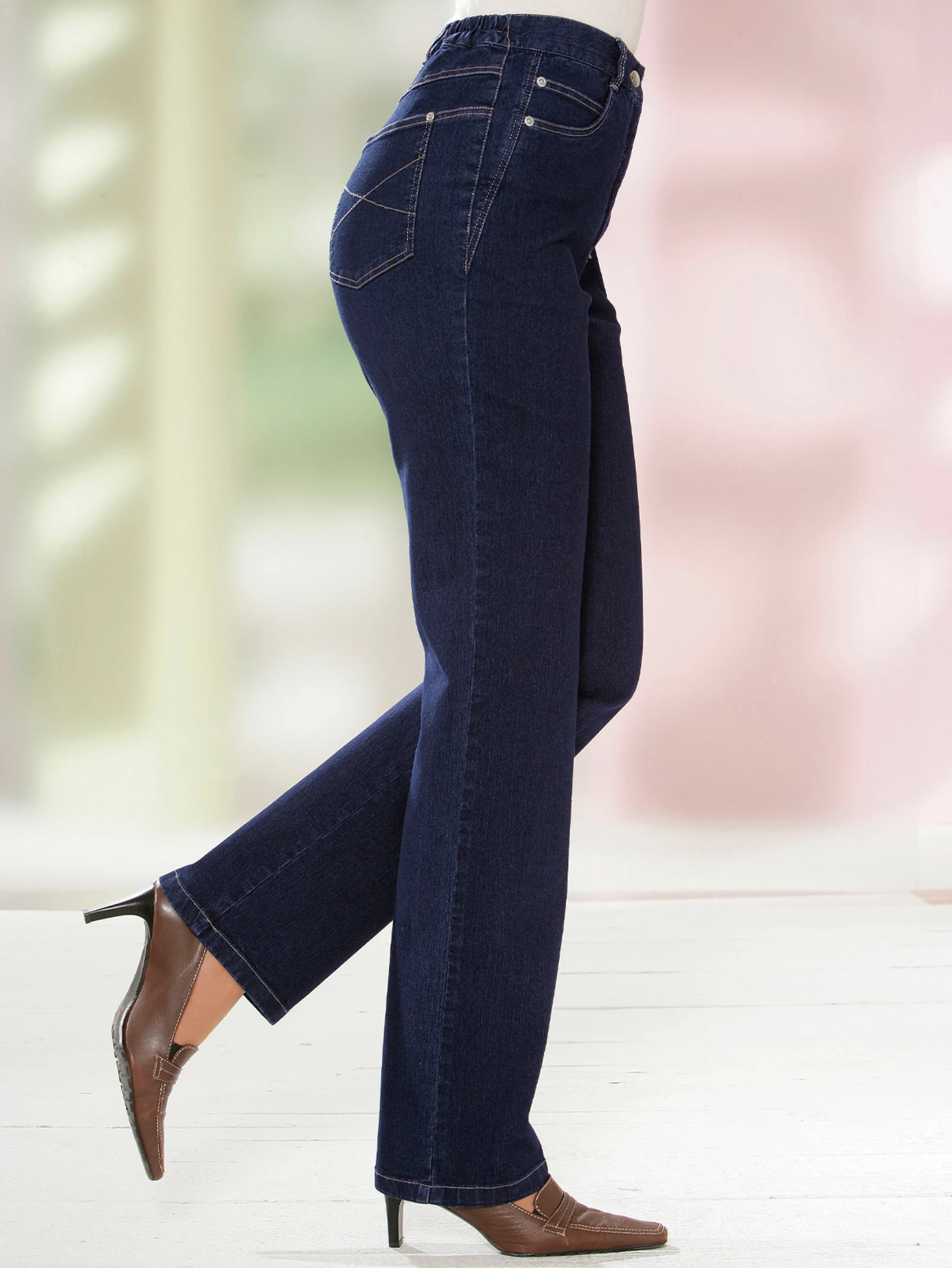 Dunkelblaue Damenjeans mit geradem Schnitt und elastischem Bund, kombiniert mit braunen Absatzschuhen. Dunkelblaue Damenjeans mit geradem Schnitt und elastischem Bund, kombiniert mit braunen Absatzschuhen.