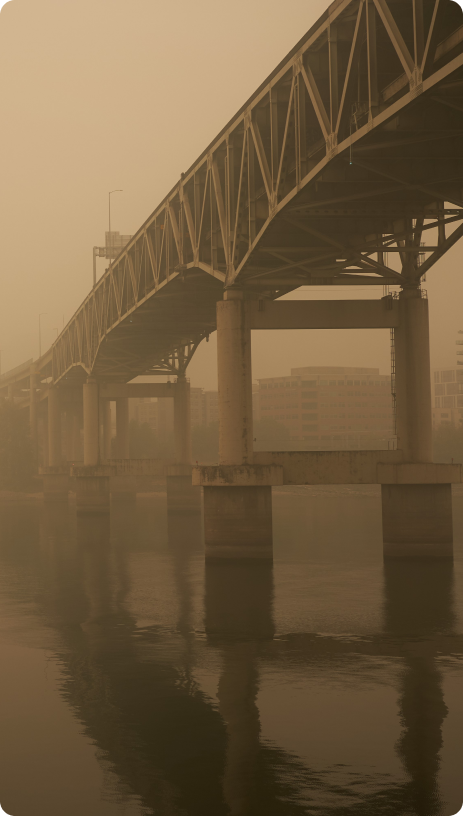 A large truss bridge over water, partially obscured by haze, with a sepia tone.