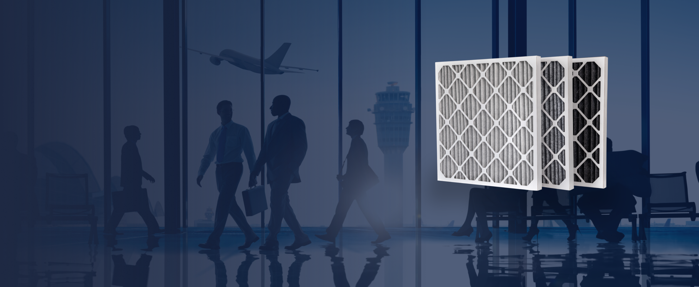 Three pleated furnace filters, appearing to be hanging on a wall in a dark, blurred background with people walking in the distance.