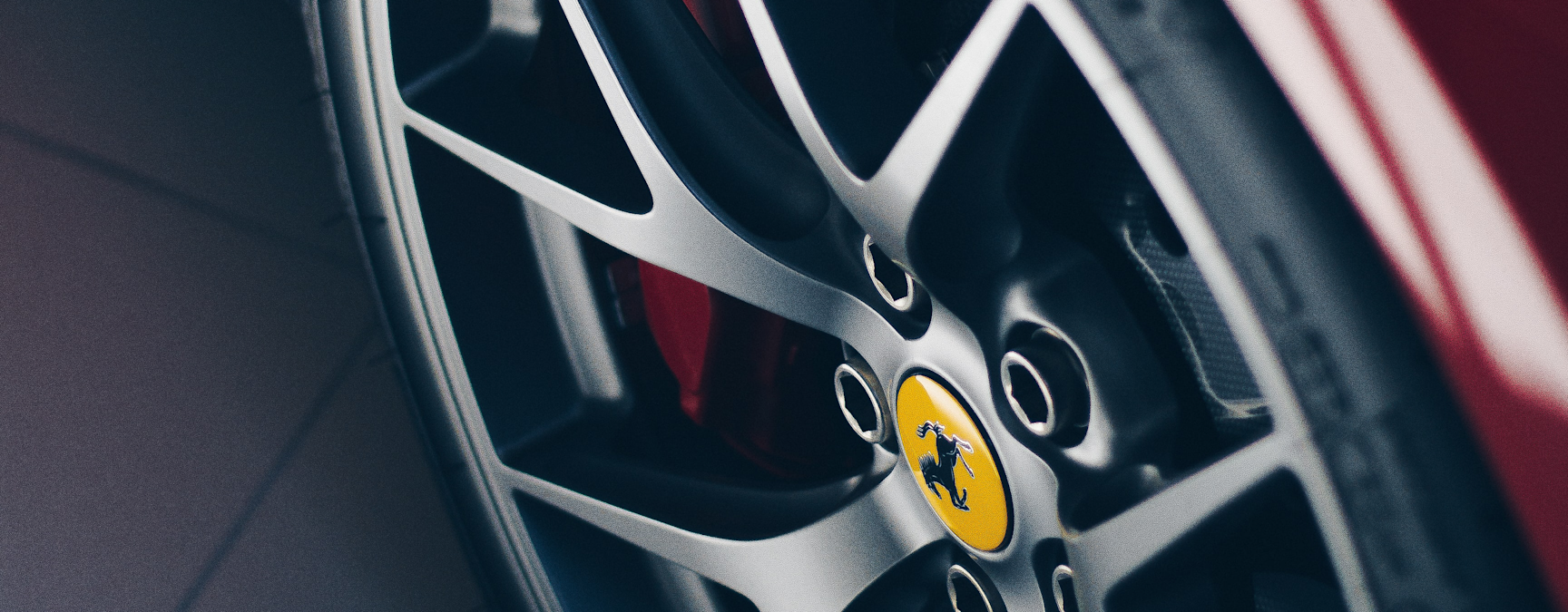 Close-up of a polished alloy wheel on a red Ferrari, featuring the iconic Ferrari logo