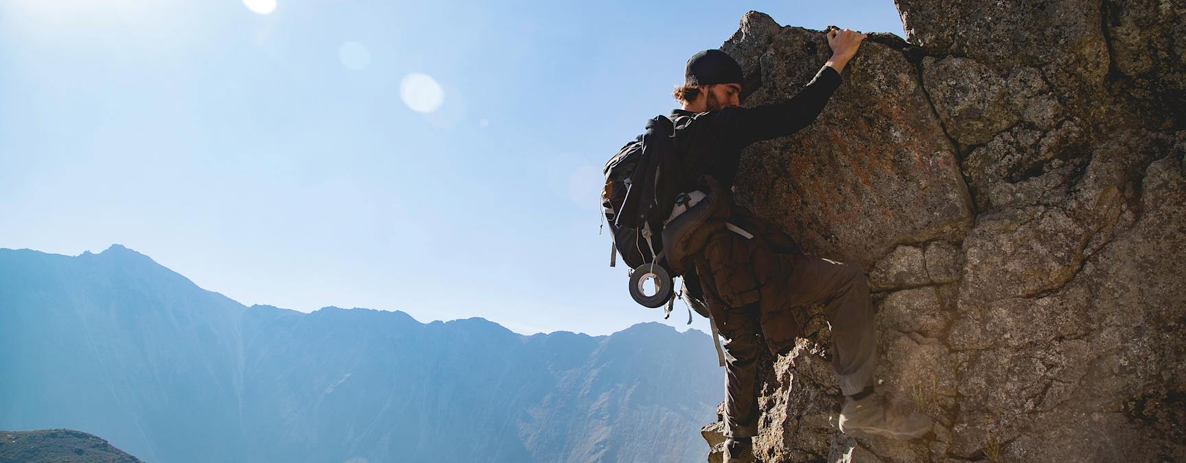 Young man rock climbing on a sunny day with a clear blue sky