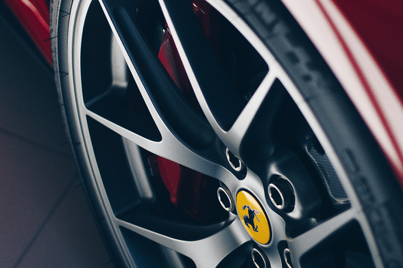 Close-up of a polished alloy wheel on a red Ferrari, featuring the iconic Ferrari logo