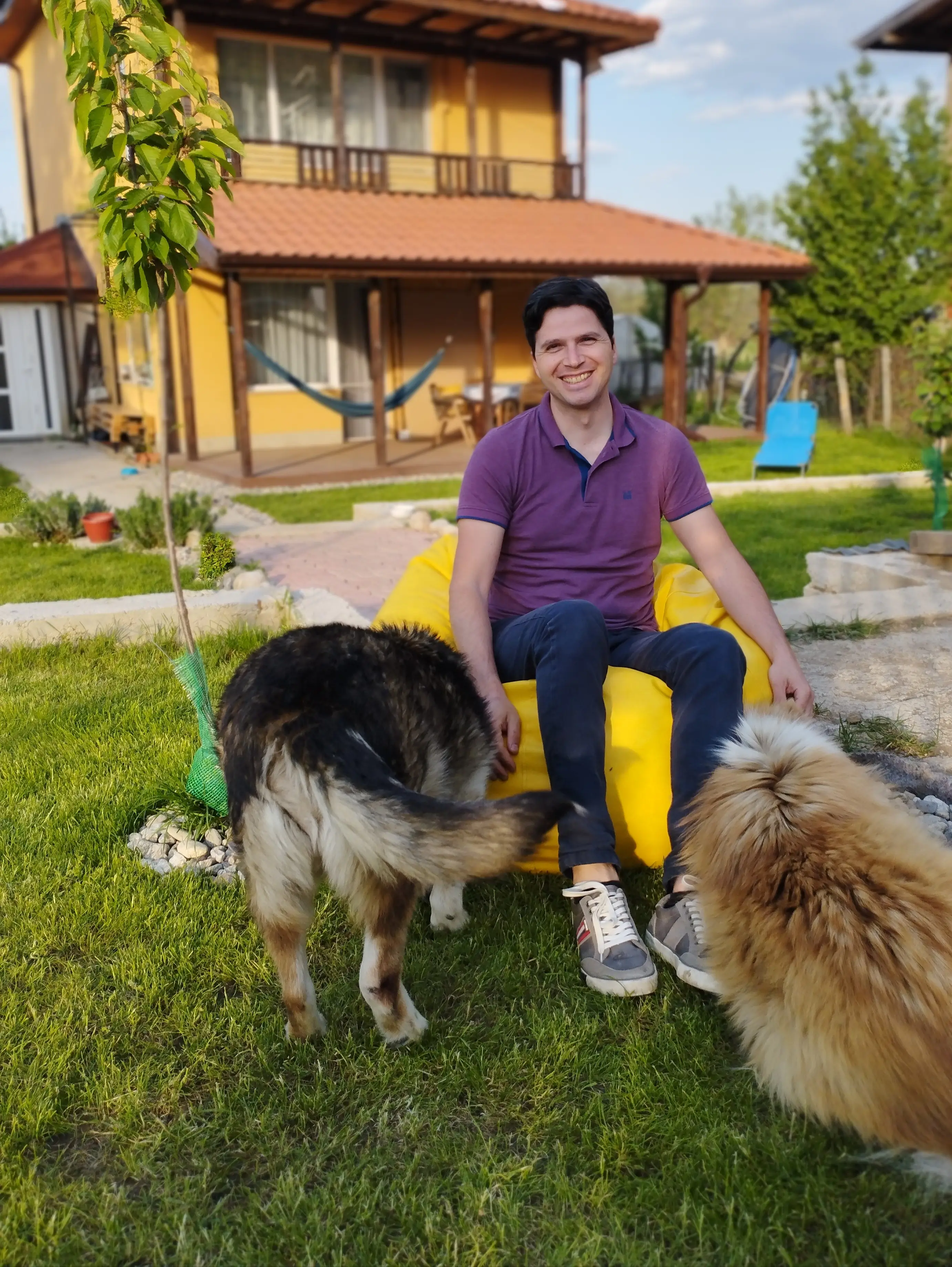 INDUSTRIA's Corda Team Lead, Nino Bonev, sitting outside his country home with his two adopted dogs, Maya and Chichi. Nino also has 7 cats.