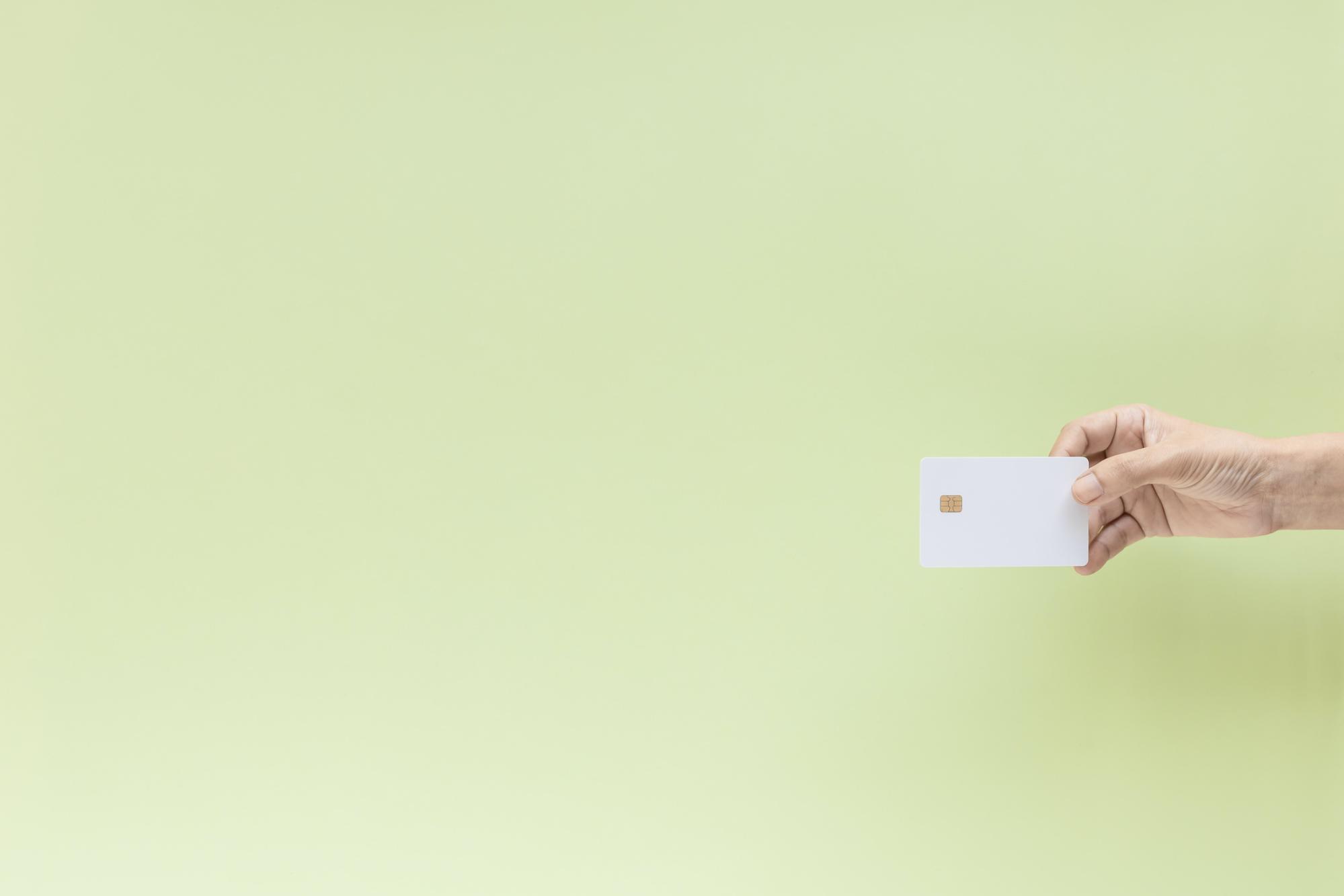mint green background with a hand holding white credit card