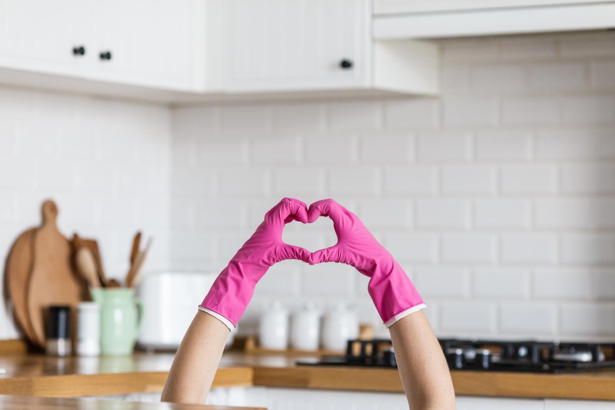 pink rubber gloves in a kitchen forming a heart 