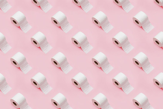 تکرار رول های کاغذ توالت در پس زمینه صورتی