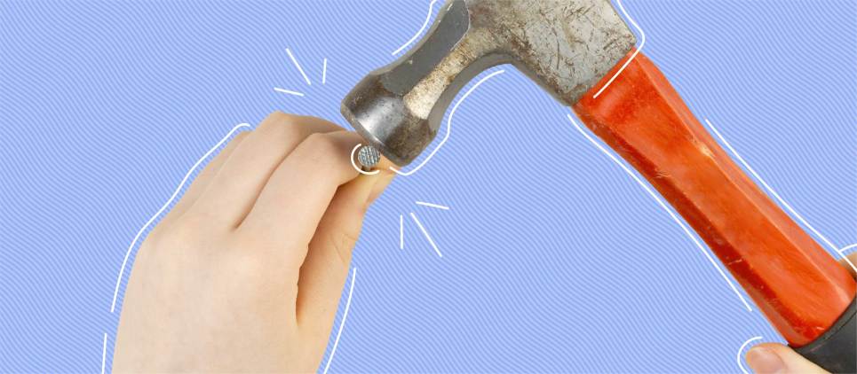 hands holding a red hammer with a nail in hand on a blue background 
