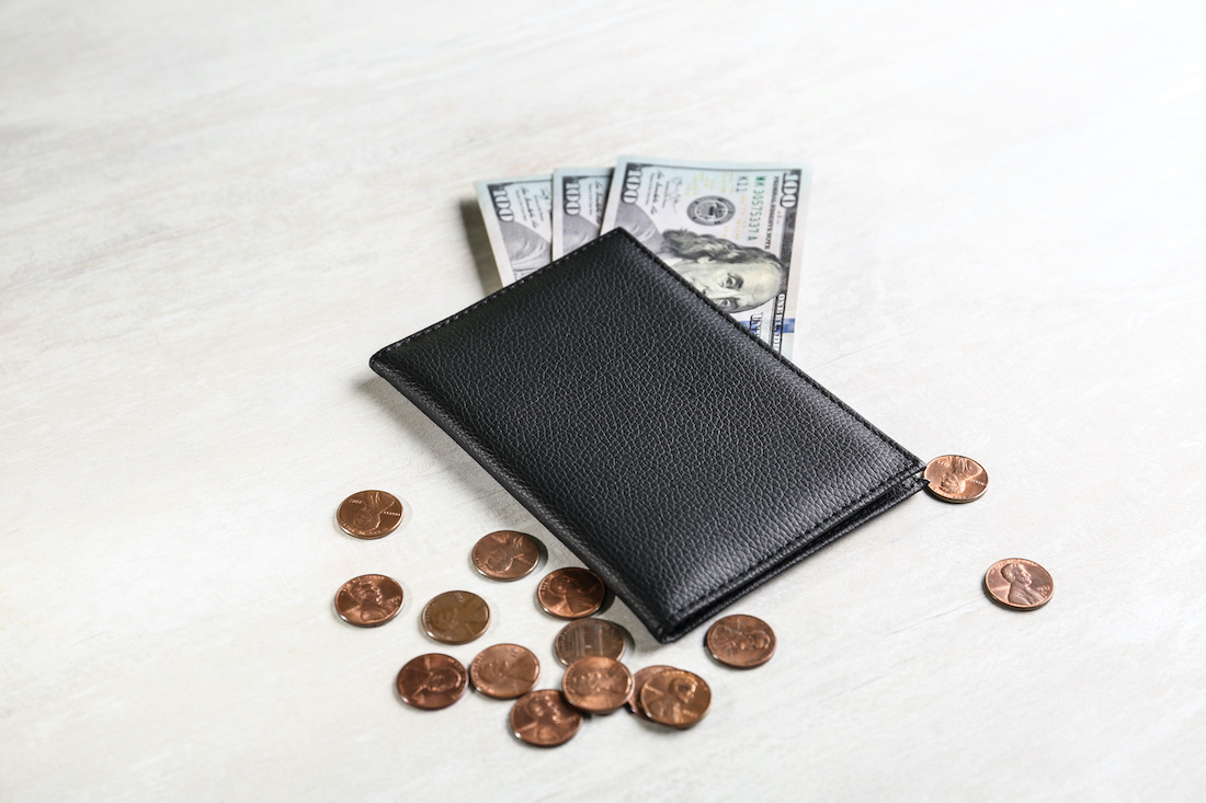 A wallet with money and pennies around it