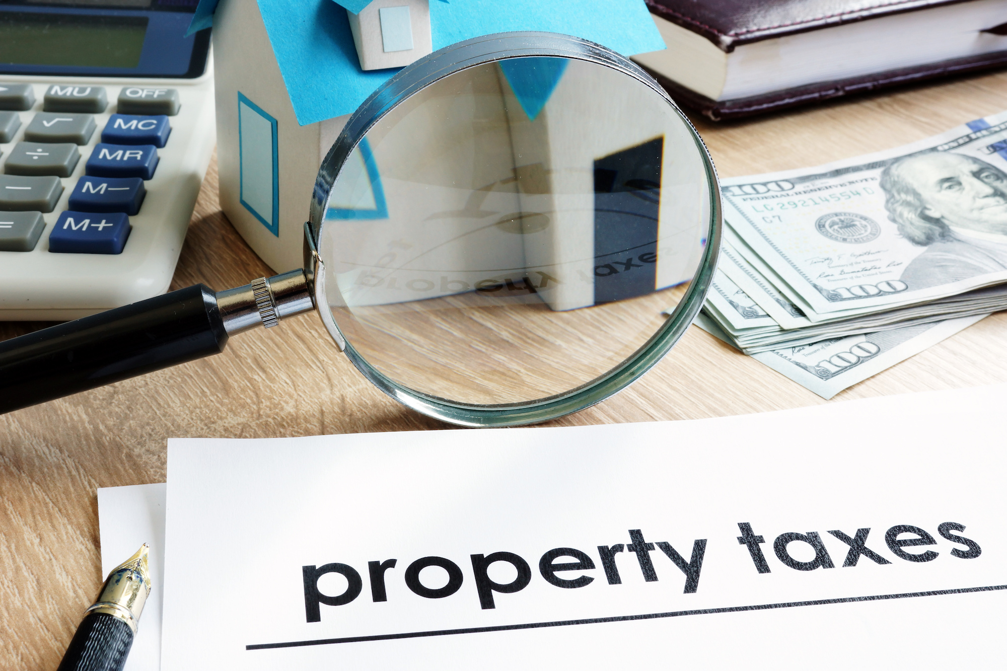 Magnifying glass sits next to a document that reads "property taxes."