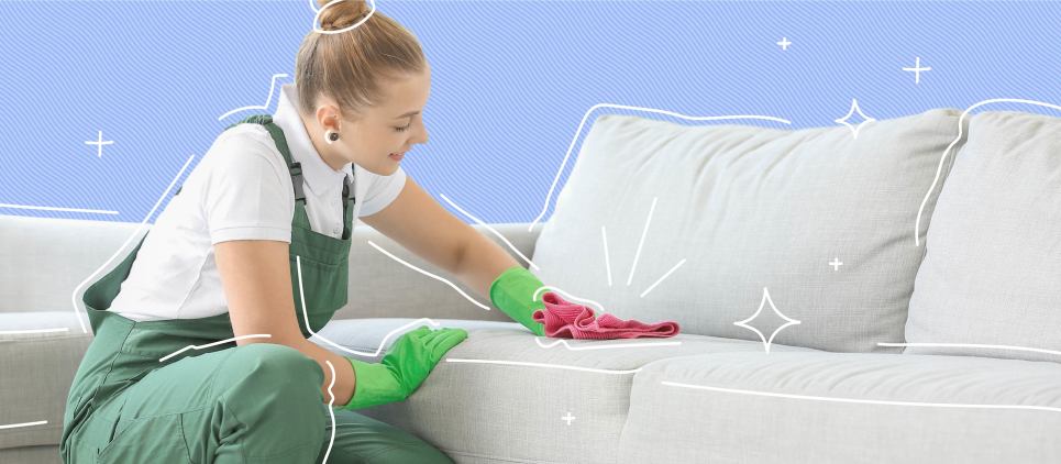Woman wearing cleaning gloves cleans couch with a cloth.