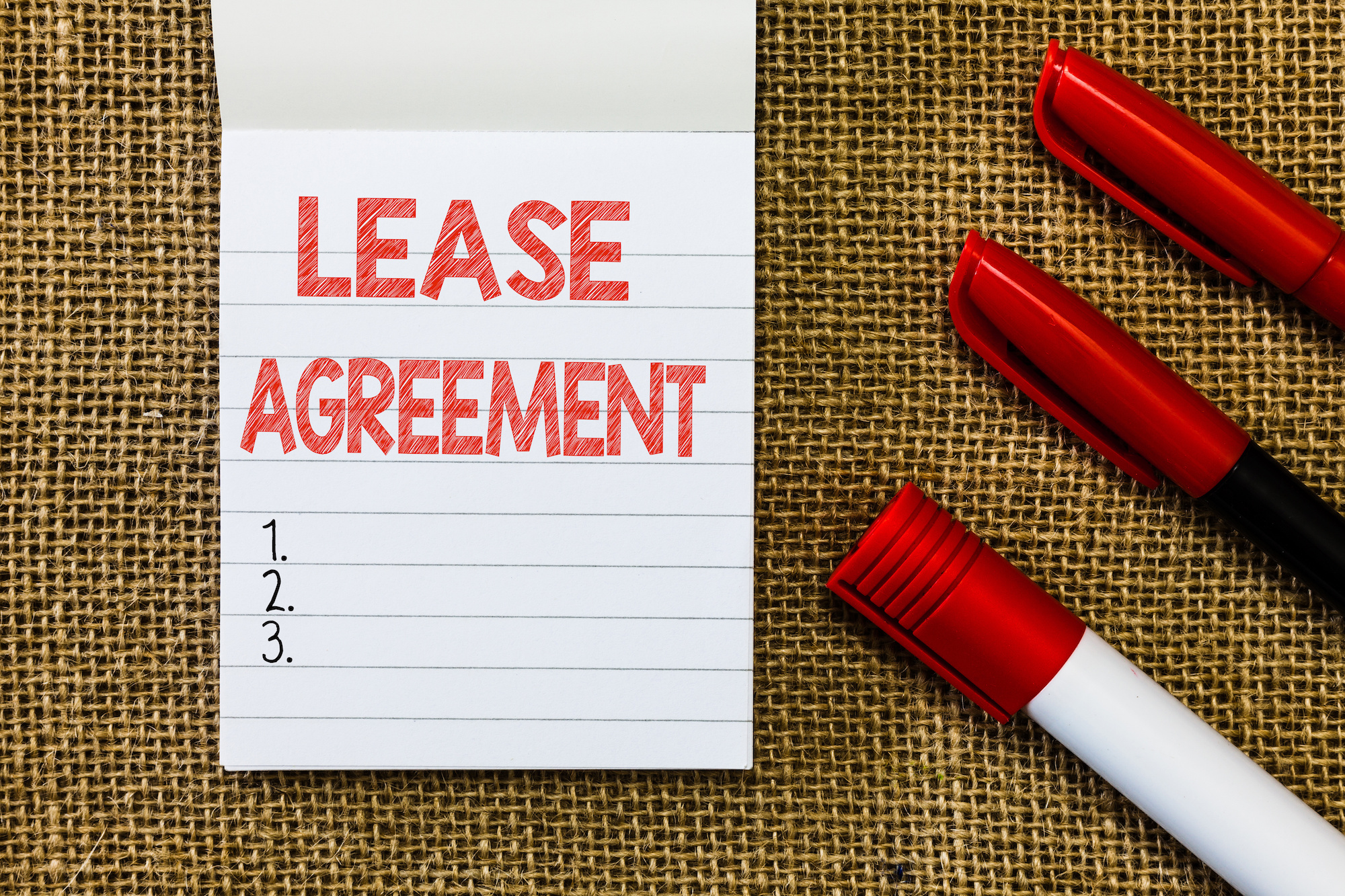 "Lease agreement" written on a notepad with three red markers.