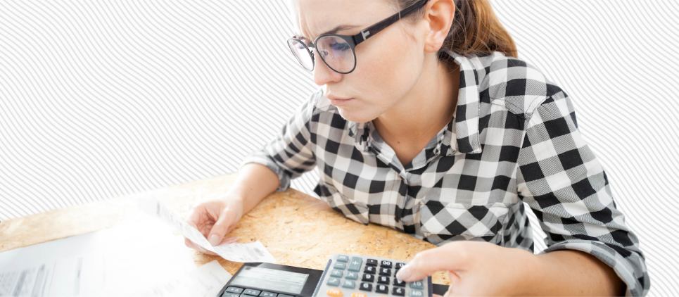 Woman looks over paper receipts with a calculator and computer.