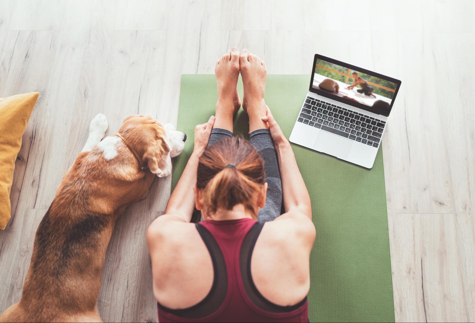 girl stretching on green yoga mat with dog