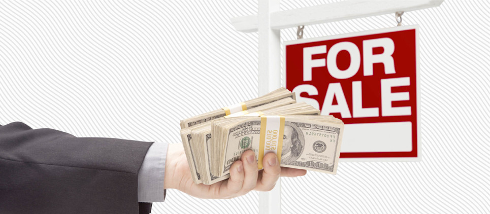 Hand with a stack of cash in front of a for sale sign. 