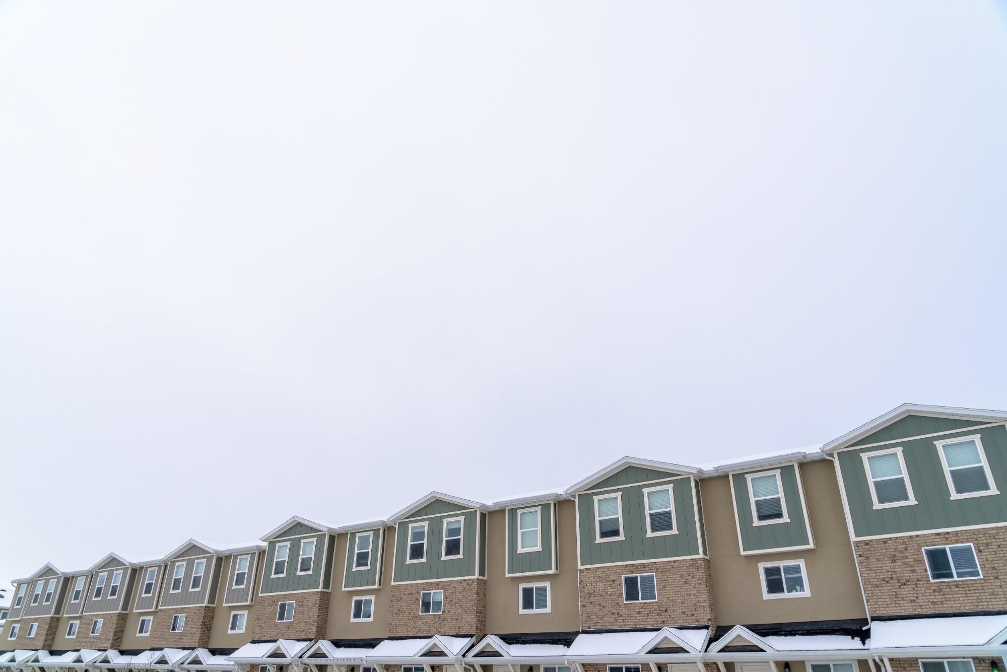 A line of townhouses lined up against a grey sky