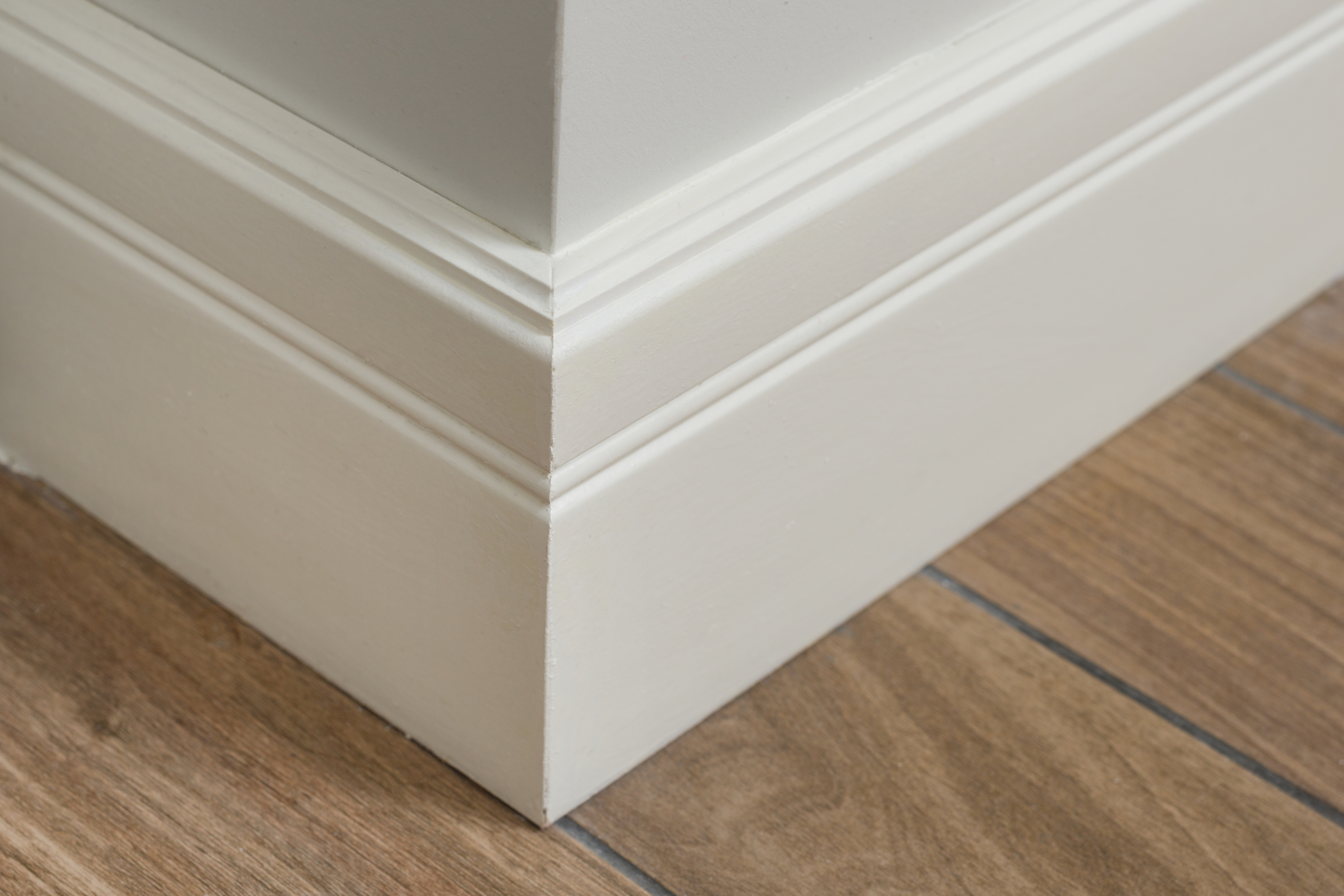 Corner of a room featuring white baseboards.