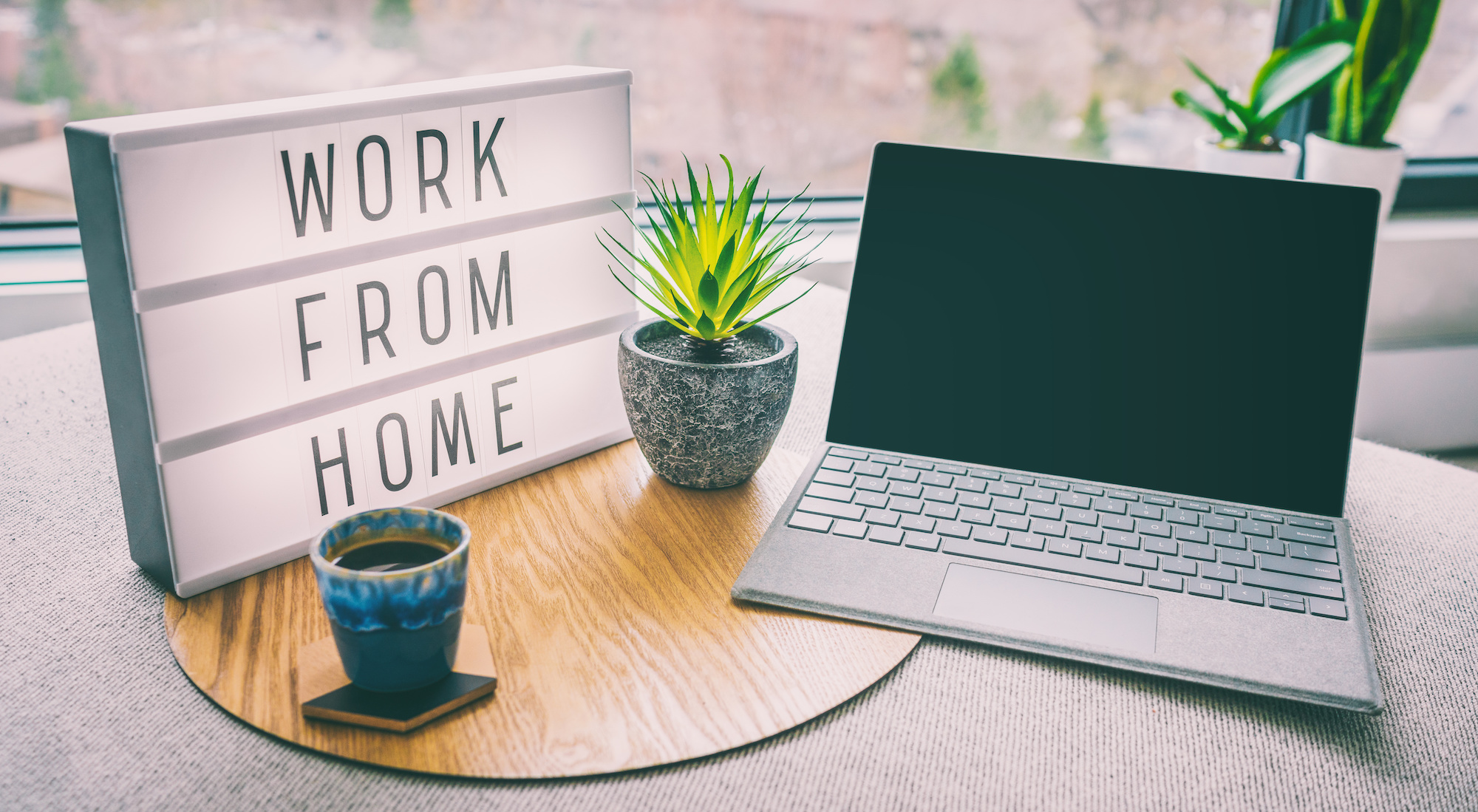 A sign that reads "work from home" next to a laptop on a desk.