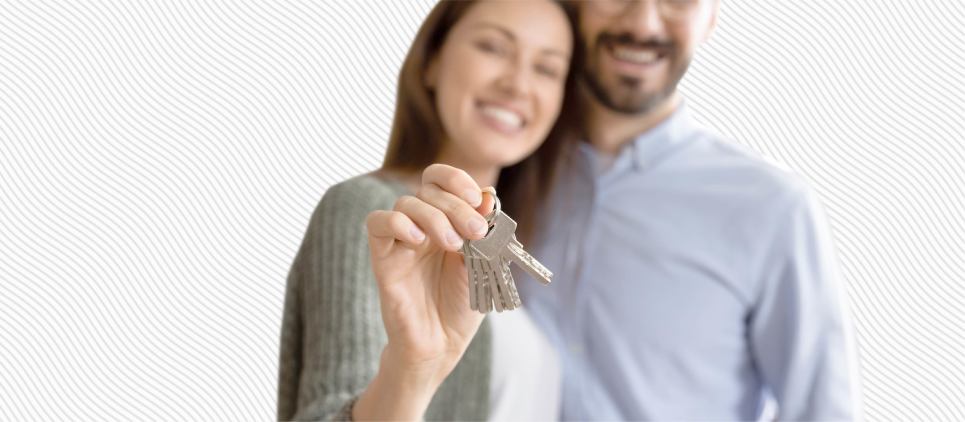 A couple embraces and holds out a set of keys. 