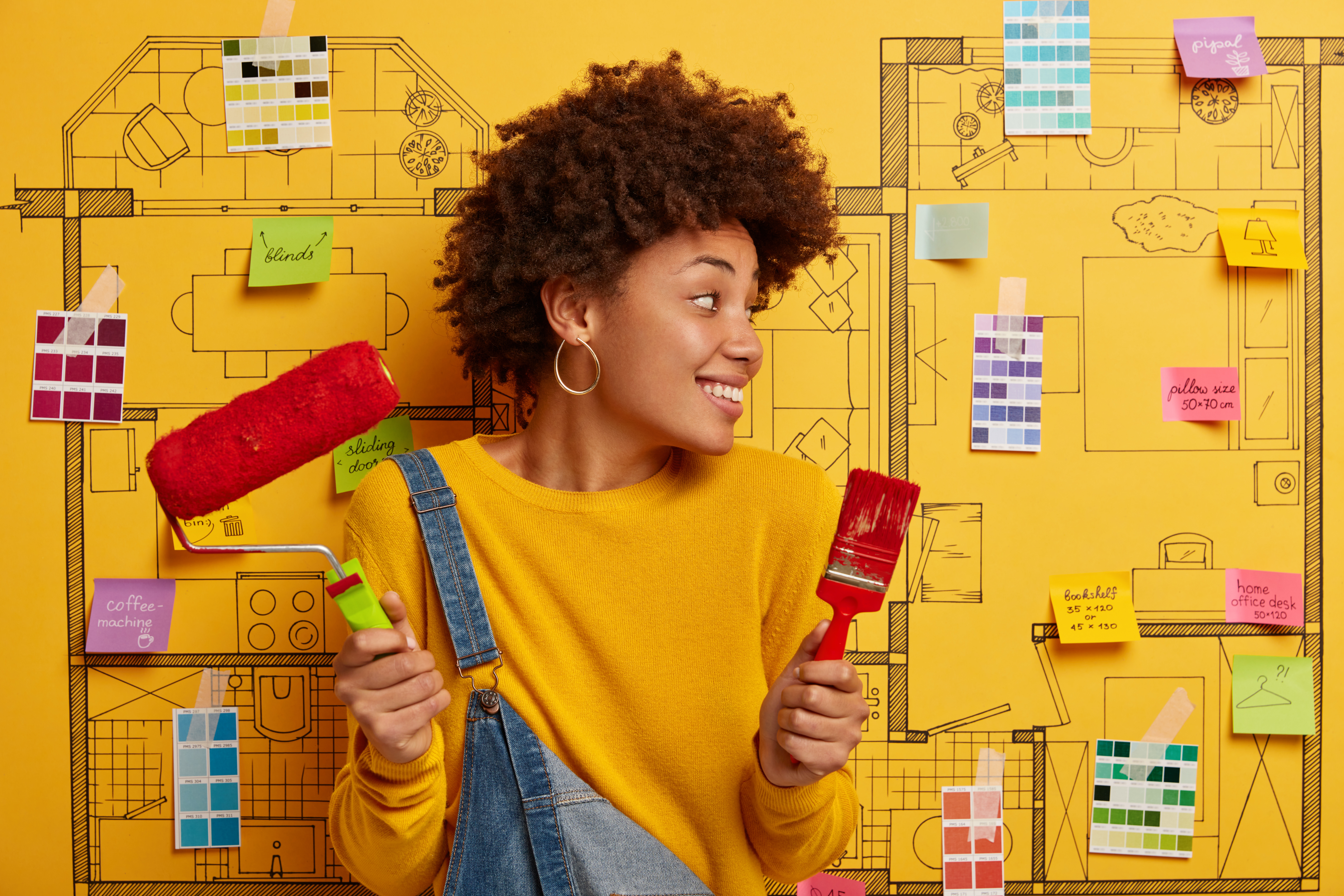 Woman stands in front of blue print of a house with different color swatches and a paint roller.