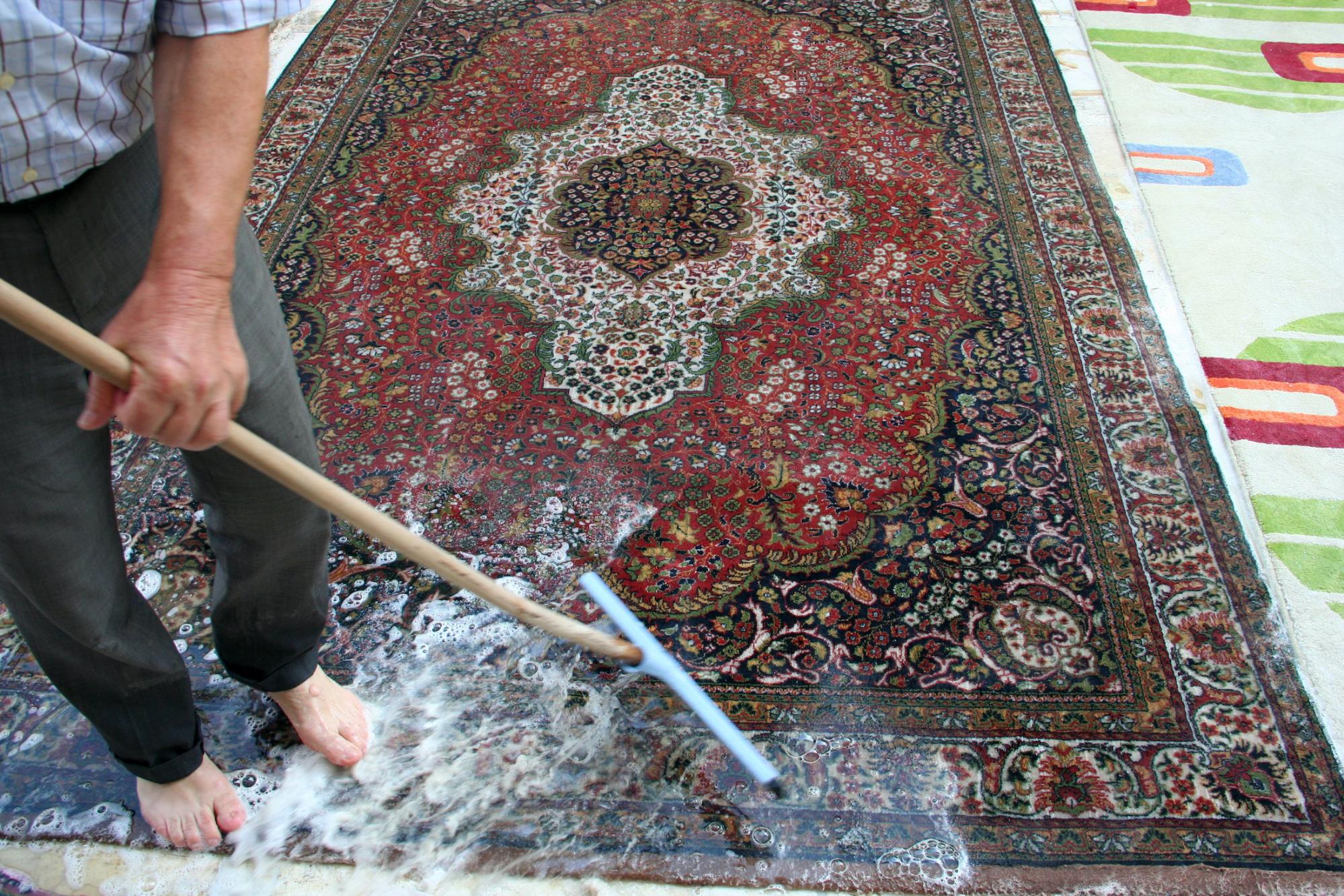 multi colored rug with person standing with a cleaning mop and soap 