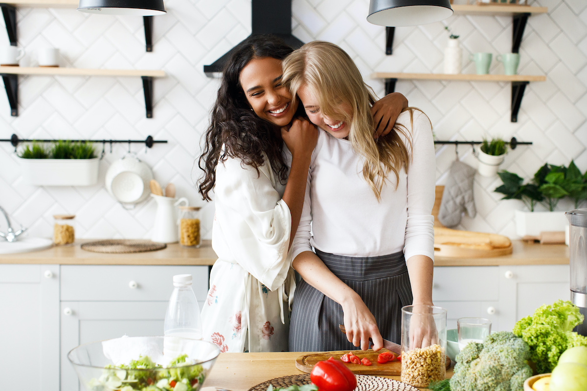 two roommates hugging and cooking together