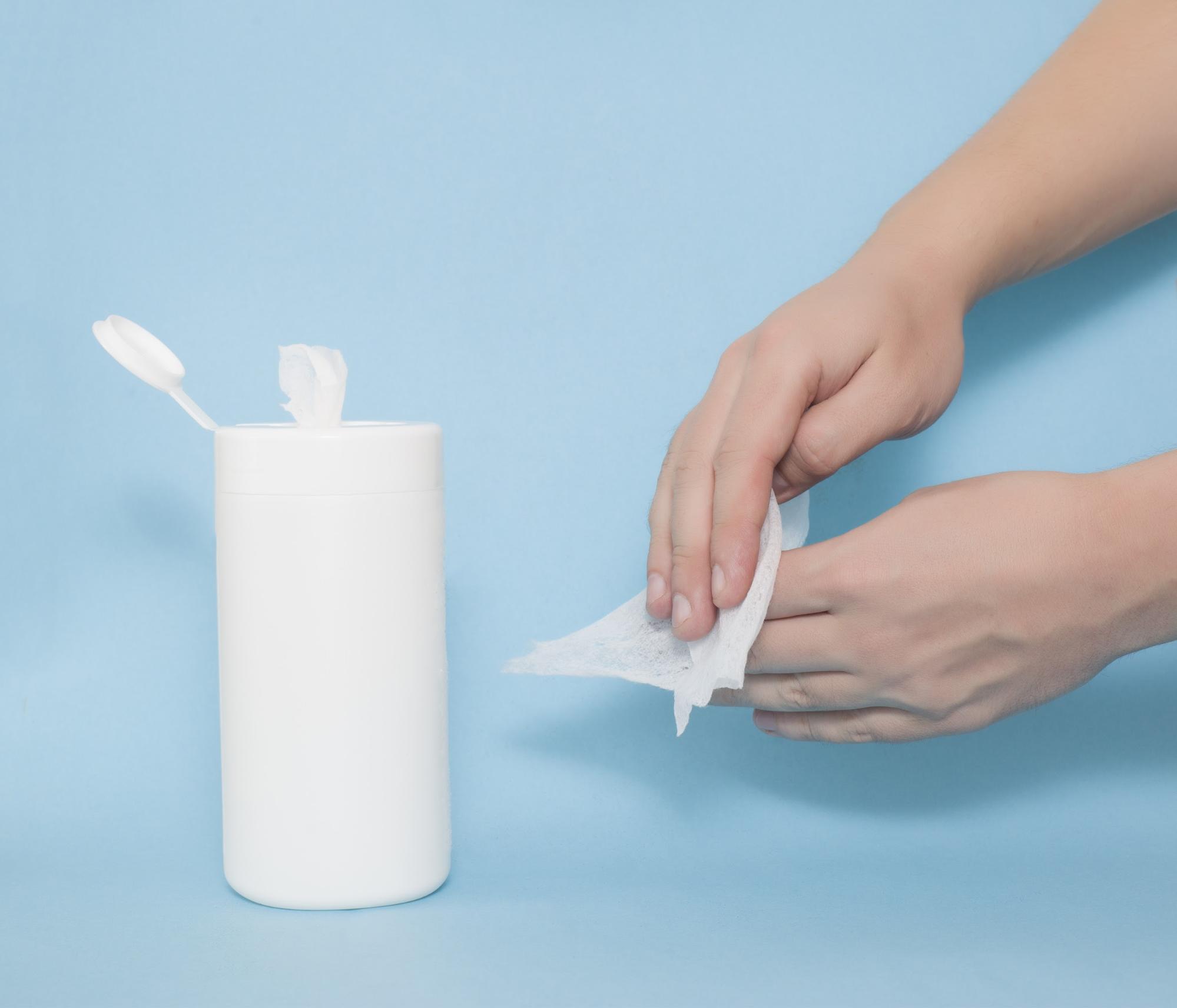 white bottle of wipes with hands using the wipe 